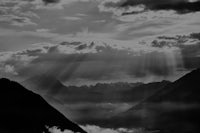 a black and white photo of mountains with rays of light